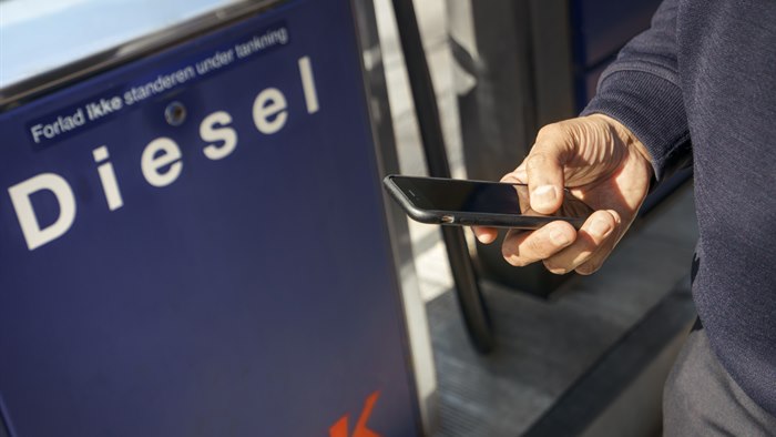 Mand holder mobiltelefon ved en OK Truck Diesel-stander