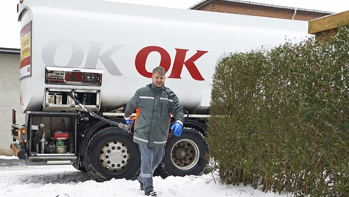 En af OK's tankvognschauffører på vej ind til hus med olieslange i hånden