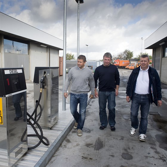 Tre mænd kommer gående ved en dieseltankstation