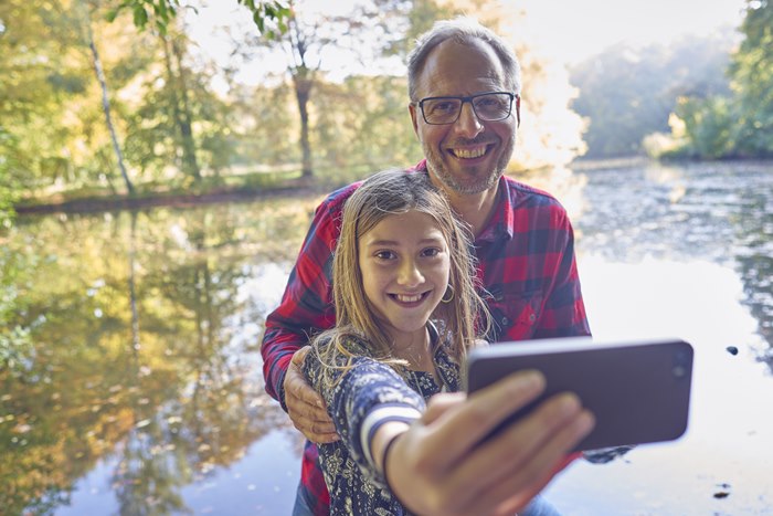 Far og datter i skoven tager selfie med mobiltelefon
