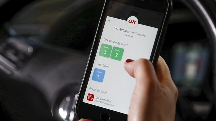 Mobiltelefon med OK's app med valg af tankstander på skærmen