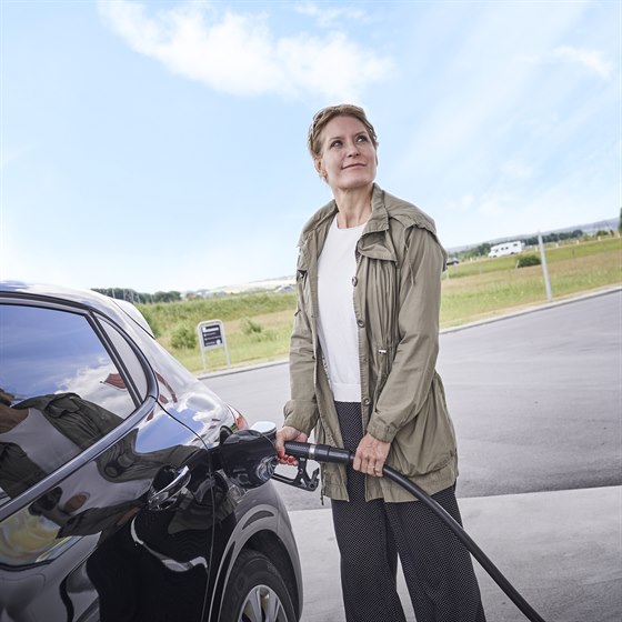 Kvinde i færd med at tanke bil hos OK