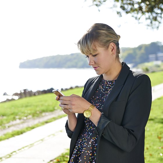 Ung kvinde står med sin mobiltelefoni