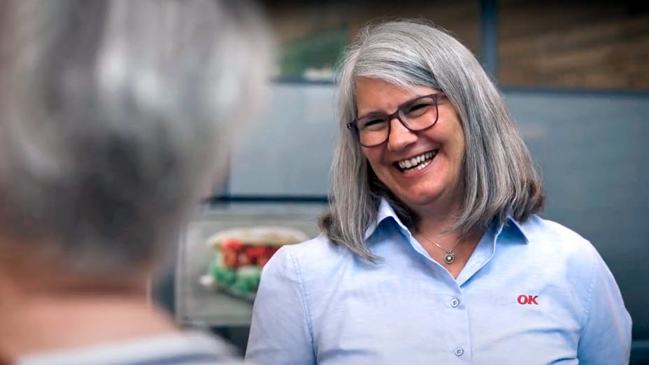 Smilende kvinde med OK-logo på skjorten