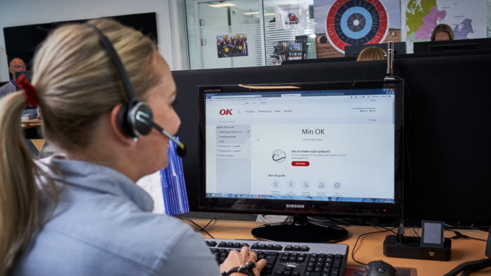 Kvinde med headset sidder foran computer med Min OK på skærmen