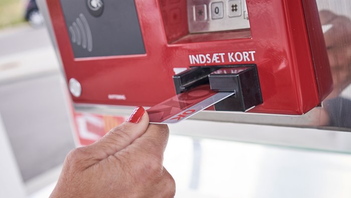 Kvinde bruger et rødt OK Kort i kortlæser på tankstation