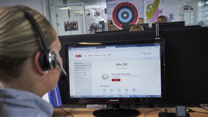Kvinde iført headset sidder foran computerskærm med OK's selvbetjening Min OK
