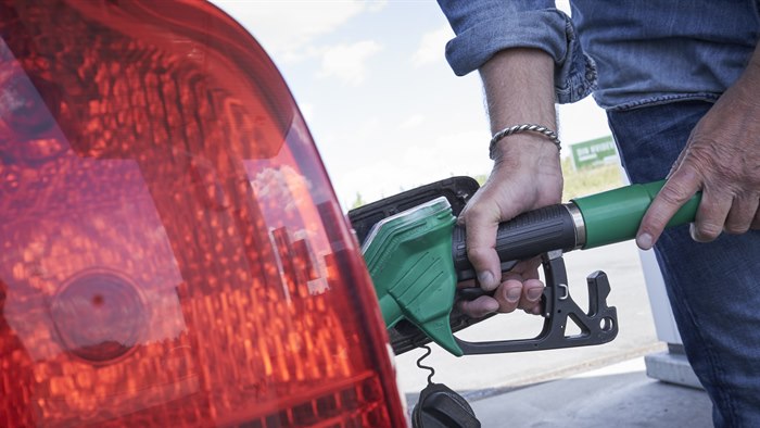 Mand står med hånden på en tankpistol i færd med at tanke brændstof