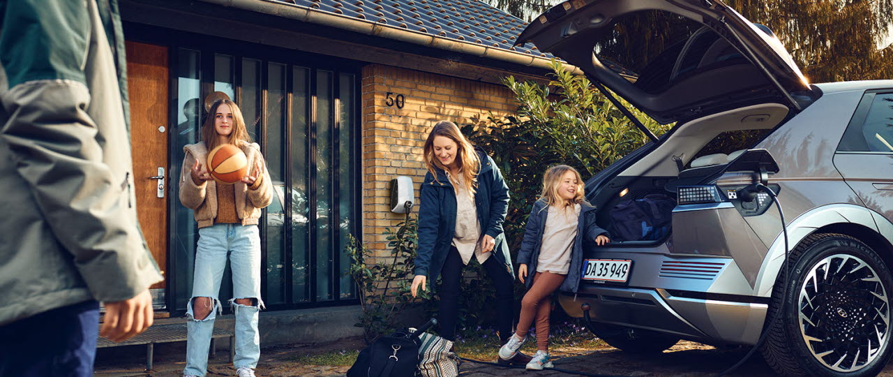 Familie ved elbil med hjemmelader