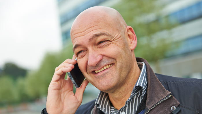 Smilende mand holder mobiltelefon op til øret