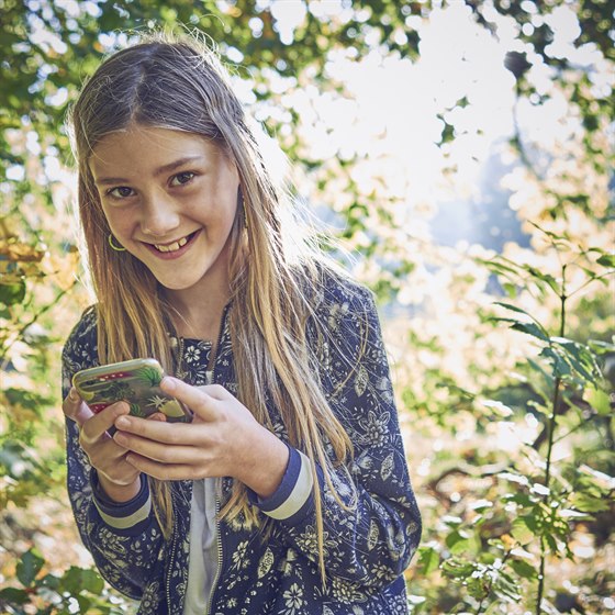 Pige i skoven med sin mobiltelefon