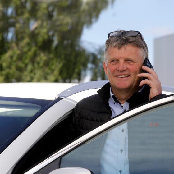 Mand snakker i mobiltelefon ved bil