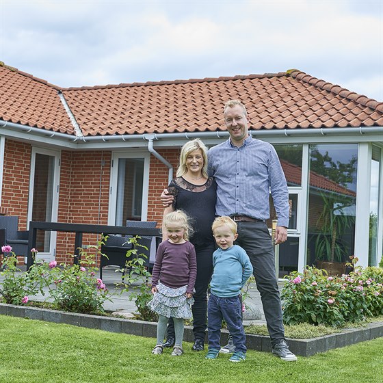 Familie samlet foran et rødt murstenshus