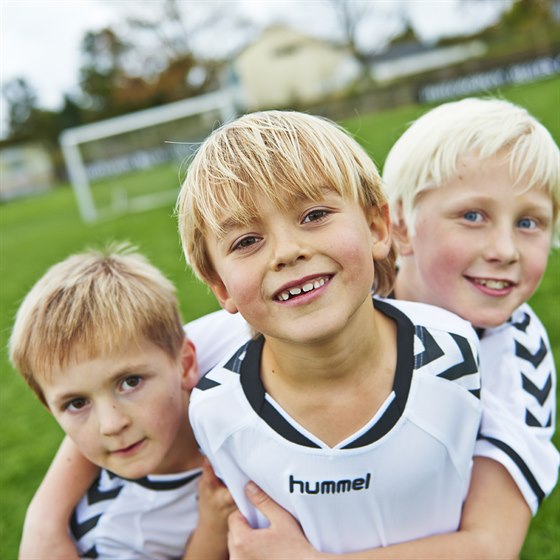 Tre fodbolddrenge iført OK fodboldtrøjer