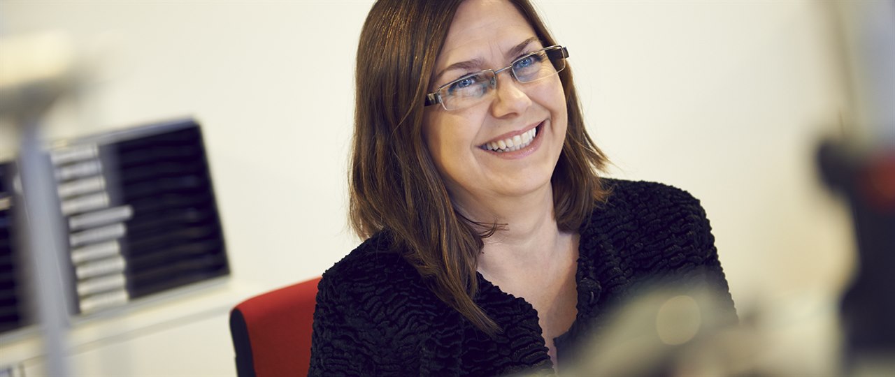 Smilende kvinde sidder i åbent kontor