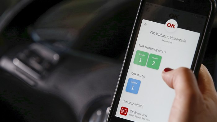 Mobiltelefon med OK's app med valg af tankstander på skærmen