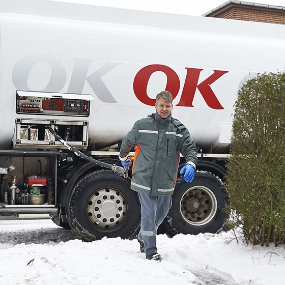 En af OK's tankvognschauffører på vej ind til hus med olieslange i hånden