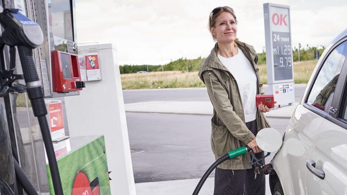 Kvinde i færd med at tanke bil på OK-tankstation