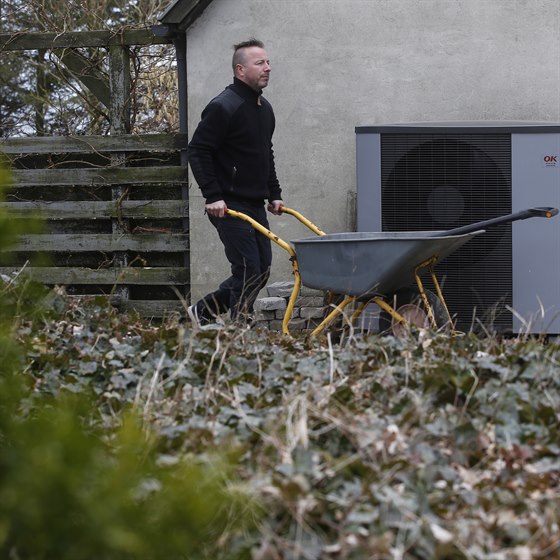 Mand går med trillebøre foran sin varmepumpe