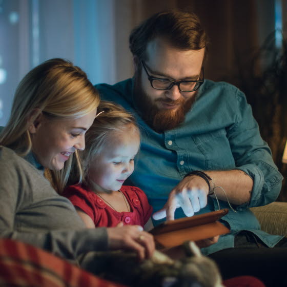 Familie sidder i sofa med tablet