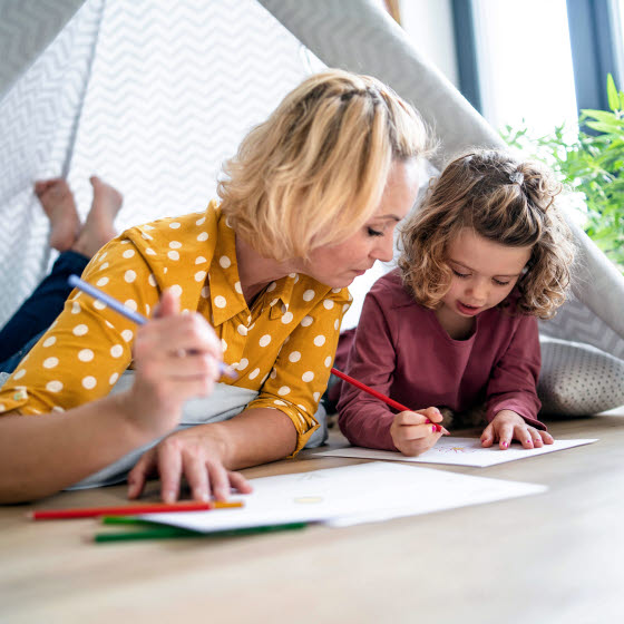 Mor og datter ligger på gulvet og tegner