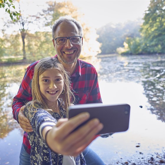 Far og datter i skoven tager selfie med mobiltelefon