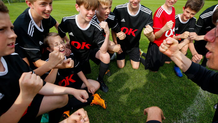Drengefodboldhold iført trøjer med OK-logo råber kampråb