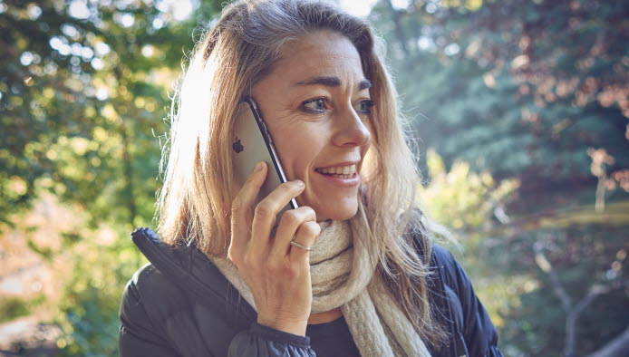 Kvinde står med mobiltelefon op til øret