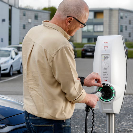 Mand ved ladestander med ladestik i hånden