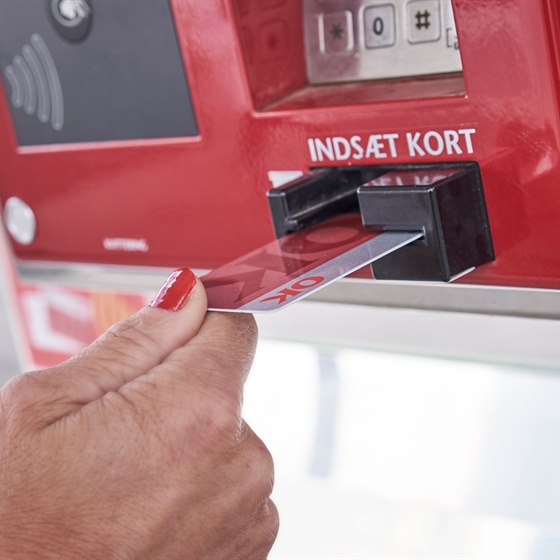 Kvinde bruger et rødt OK Kort i kortlæser på tankstation