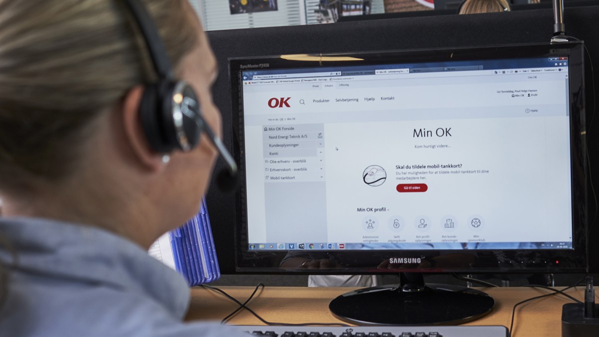 Kvinde sidder ved computerskærm med OK's selvbetjening Min OK foran sig