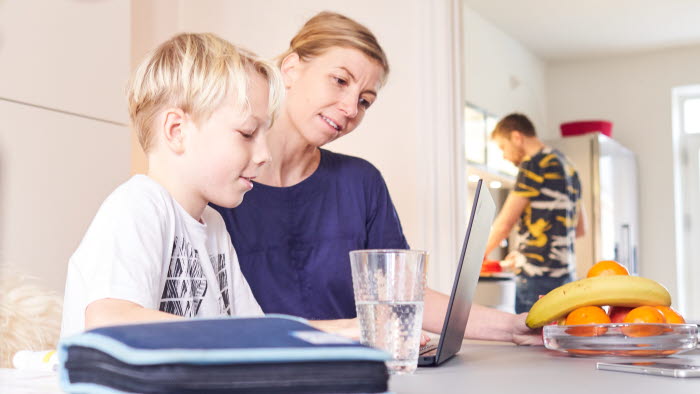 Mor og søn sidder ved spiseborg med PC foran sig