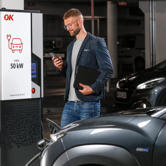 Mand med smartphone i hånden ved 50 kW ladestander