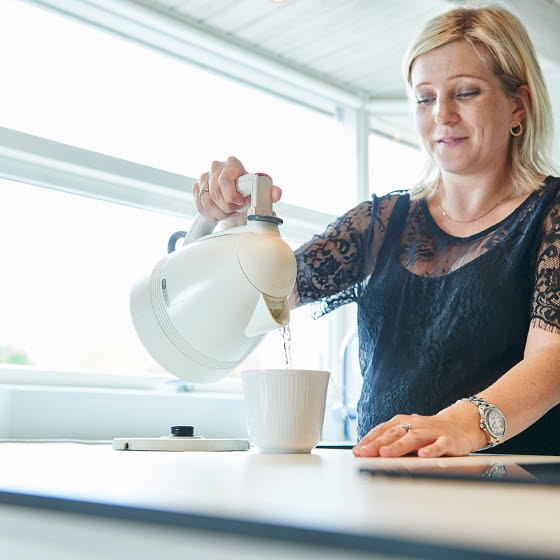 Kvinde hælder vand fra elkedel op i en kop