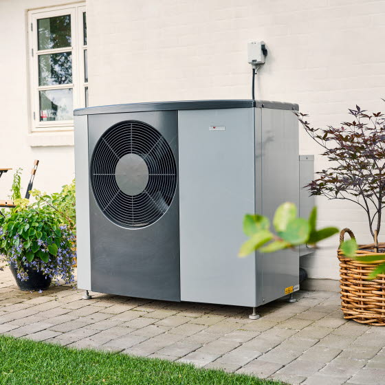 Varmepumpe står på terrassen foran et hvidt hus