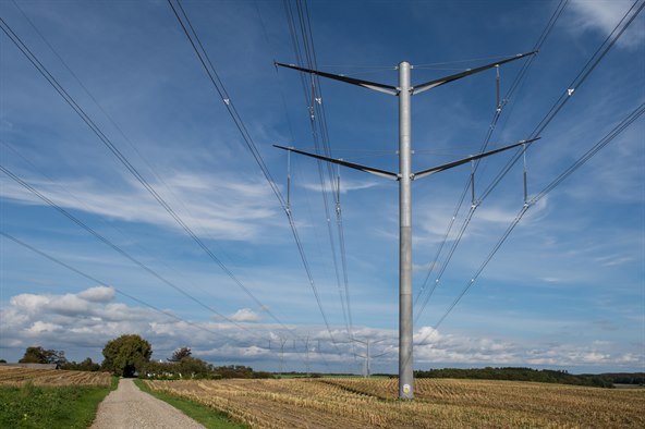 Højspændingsmast på kornmark med blå himmel