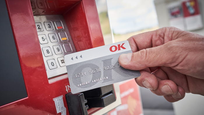 Hånd med et OK Erhvervskort ved en betalingsautomat
