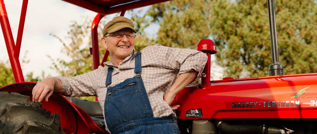 Mand læner sig op af rød traktor