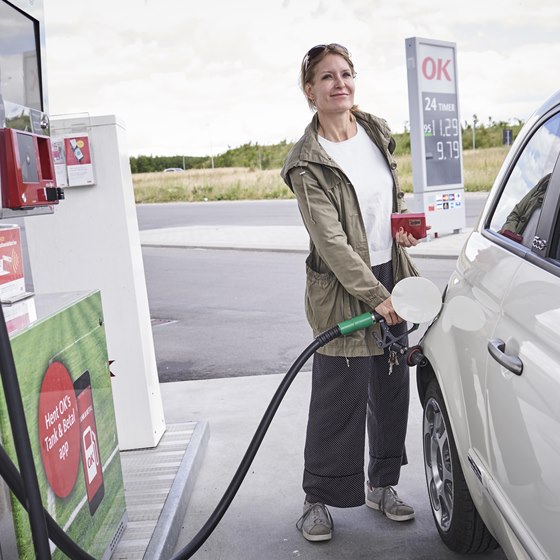 Kvinde i færd med at tanke bil på OK-tankstation