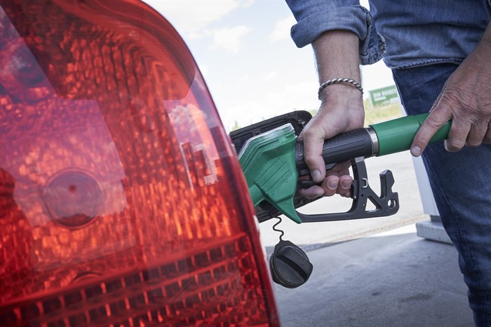 Mand står med hånden på en tankpistol i færd med at tanke brændstof