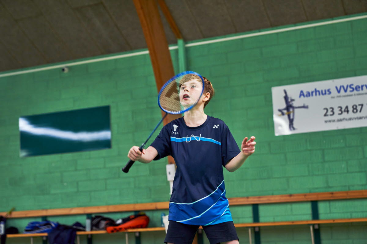 Dreng spiller badminton i hal