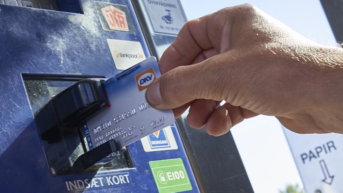 Hånd holder et OK-DKV-kort op til en betalingsautomat