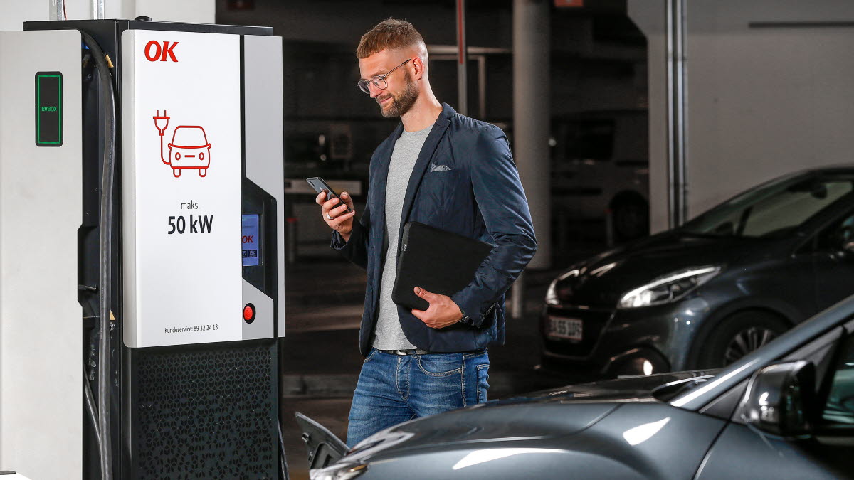 Mand med smartphone i hånden ved 50 kW ladestander