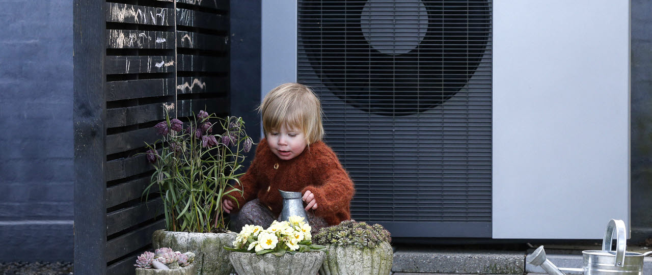 Lille barn sidder foran en varmepumpe