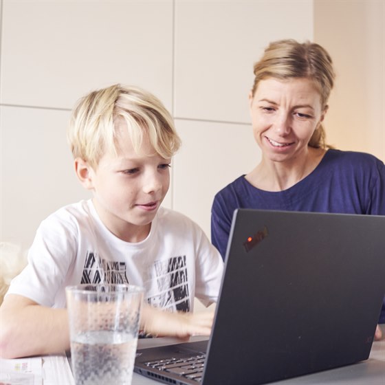 Dreng og mor sidder foran bærbar PC sammen