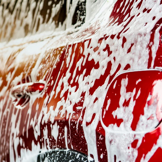 Rød bil i bilvask med skum