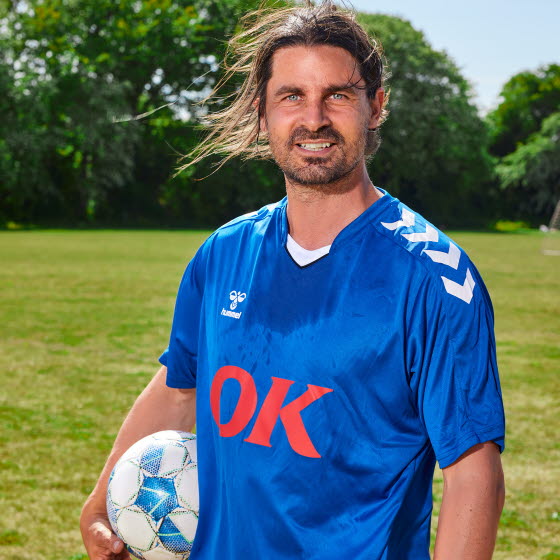 Fodboldspiller med bold under armen på fodboldbane