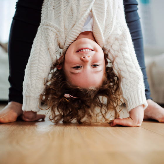 Lille pige står på hænder og smiler