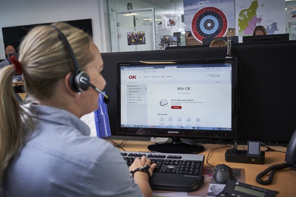 Kvinde med headset sidder foran computer med Min OK på skærmen