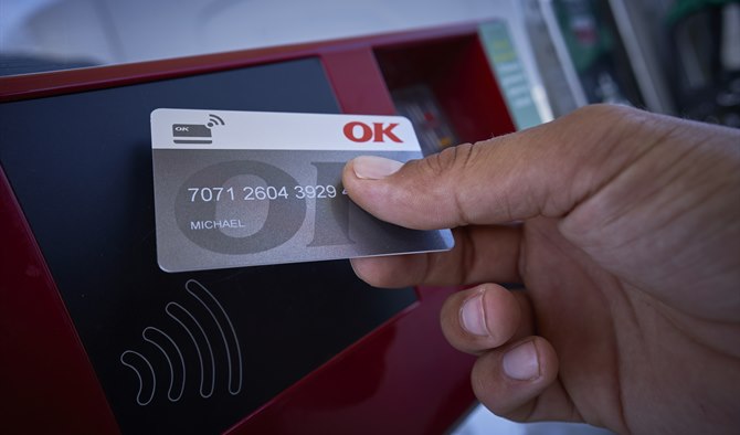 Hånd med et OK Erhvervskort ved kontaktfri betalingsautomat